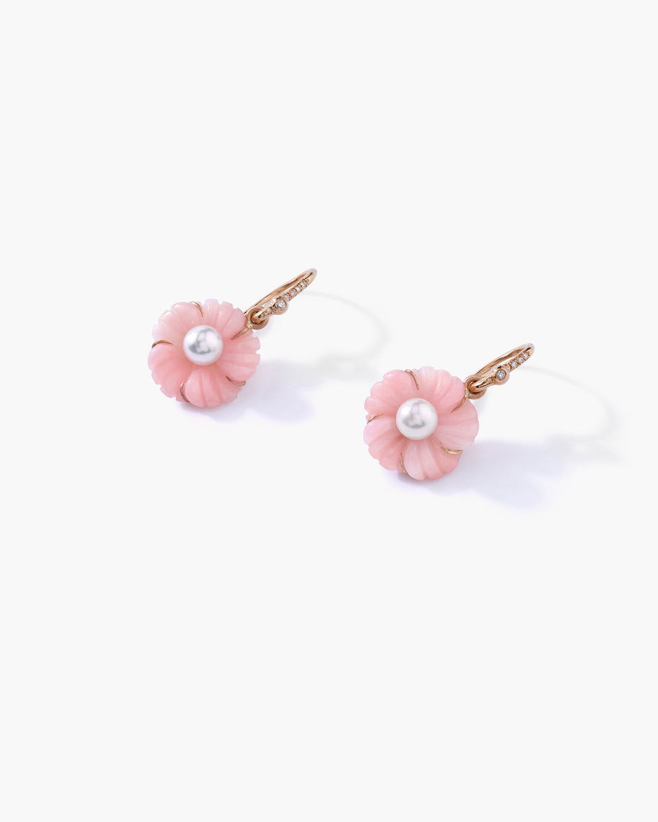 A pair of gold-tone flower-shaped earrings with light pink petals and a white pearl center, displayed on a clean white background.