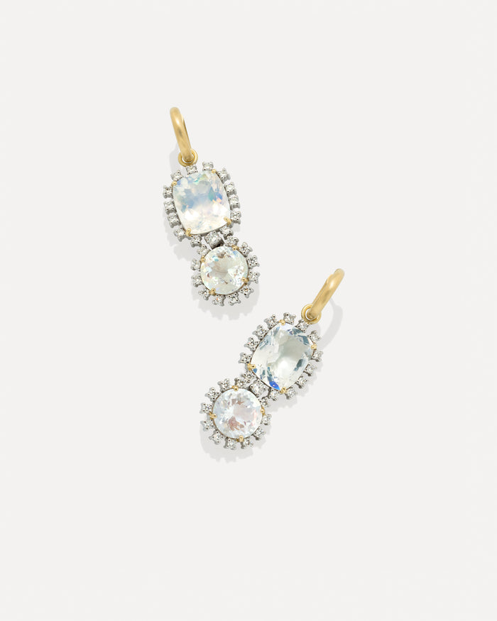 A pair of gold and silver drop earrings featuring oval and round iridescent rainbow moonstone gemstones surrounded by small diamond stones, set against a light gray background.